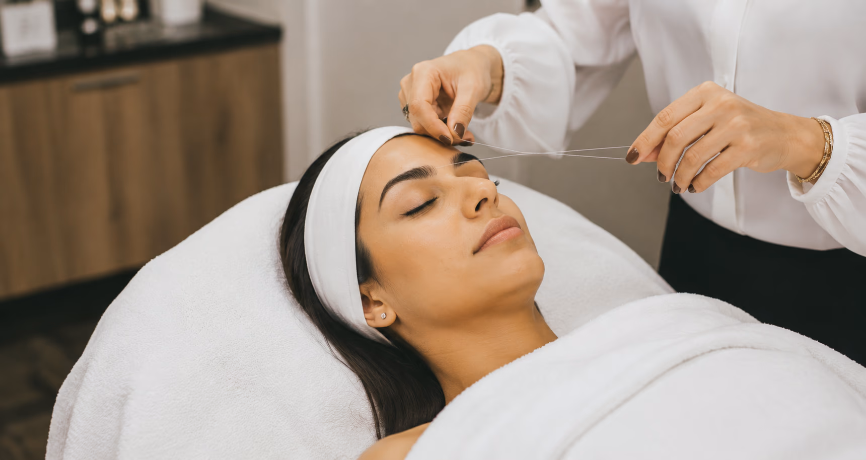 A woman relaxing during an eyebrow threading treatment at the salon